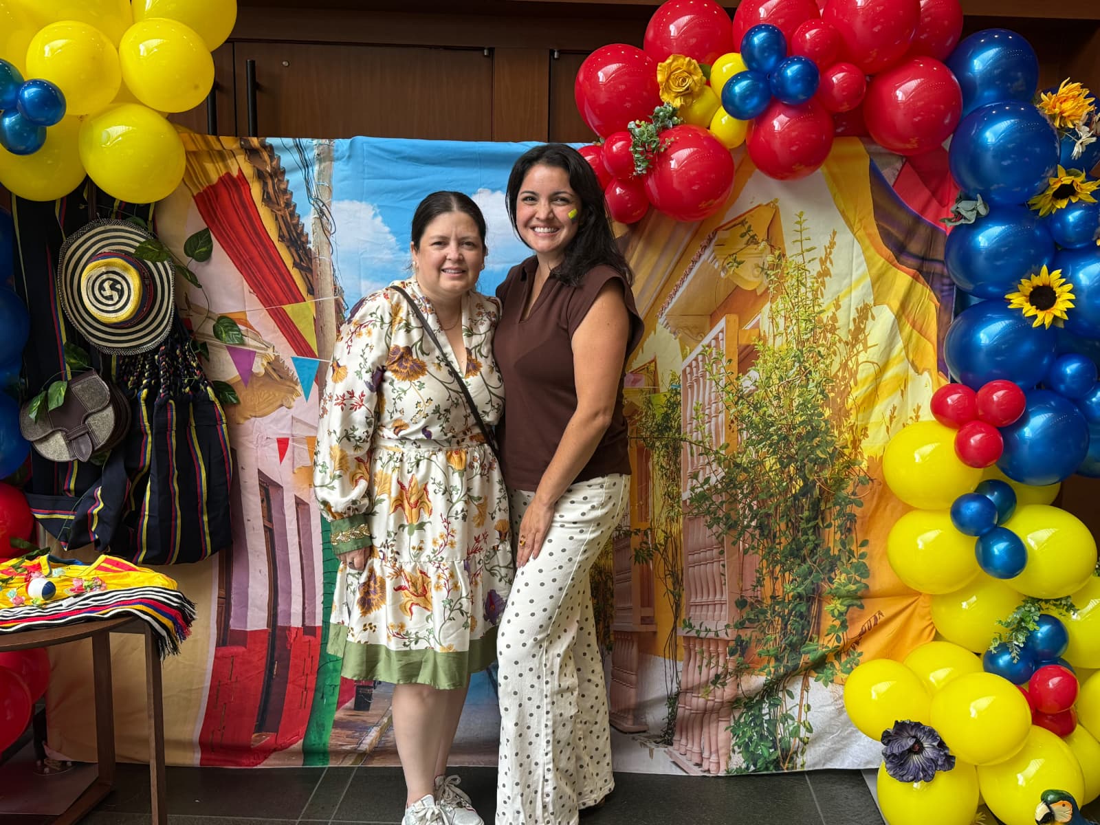 Invitadas junto a una instalación de globos con colores colombianos