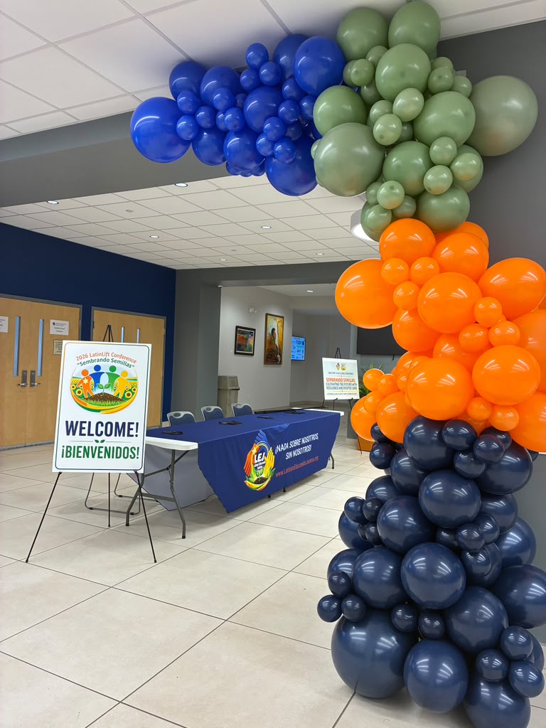 Arco de globos azul, verde y naranja en la entrada de una conferencia